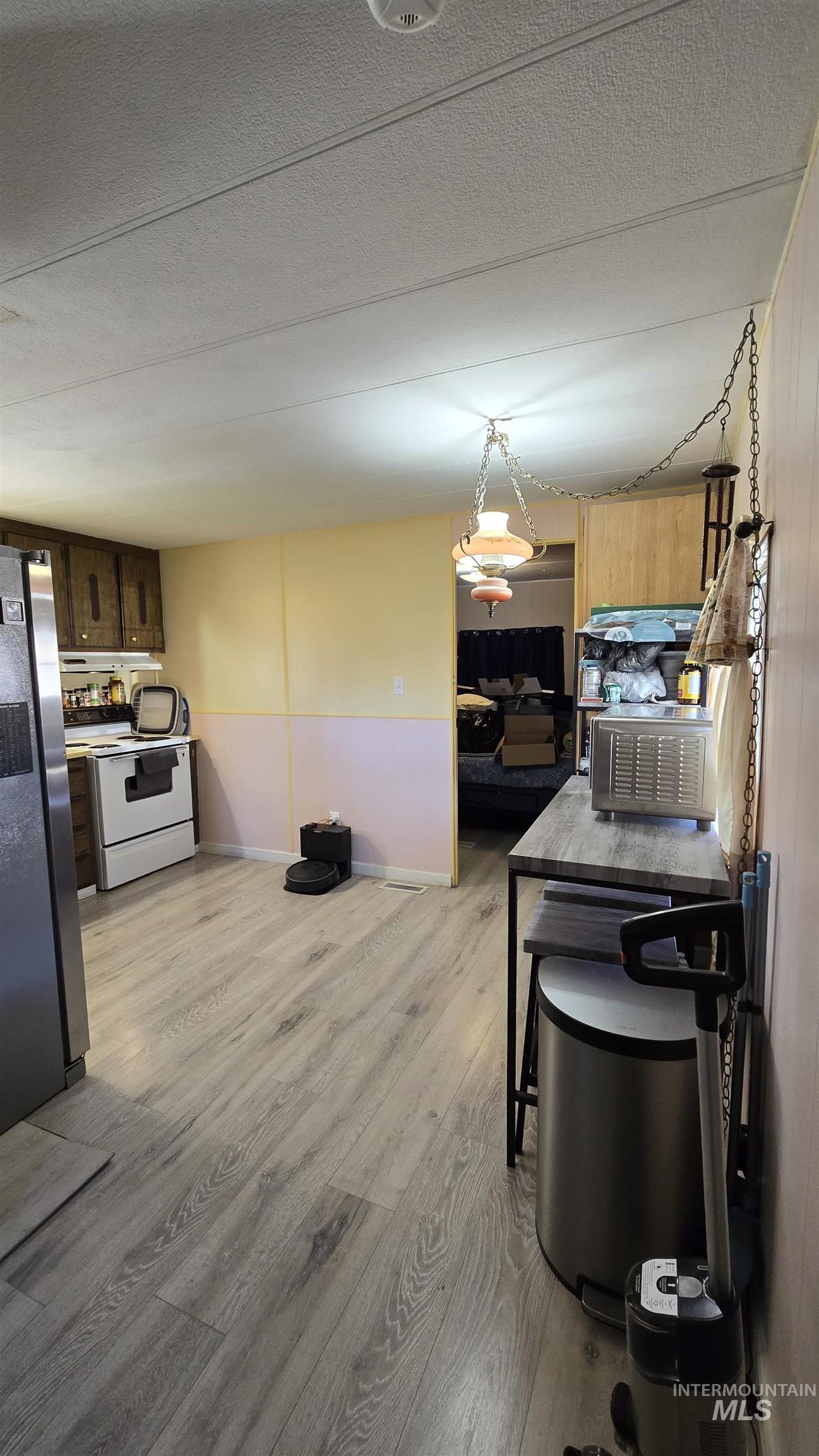 798 Dolson Lane Eagle, ID 83616 - Photo 18 of 33 Kitchen with light wood-style floors, freestanding refrigerator, dark wood finish cabinets, a textured ceiling, and white range with electric stovetop