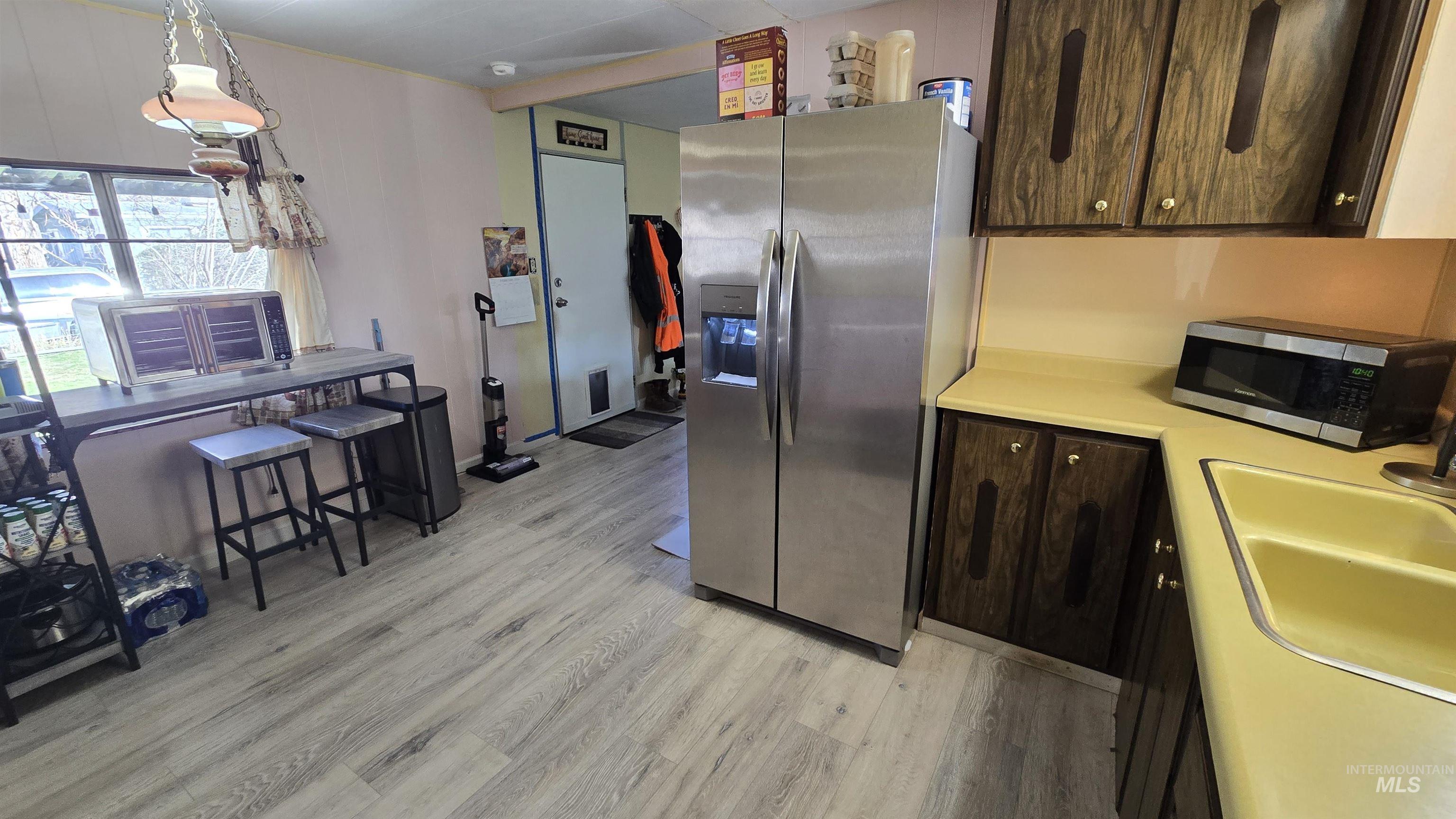 798 Dolson Lane Eagle, ID 83616 - Photo 19 of 33 Kitchen featuring stainless steel appliances, light countertops, dark wood finish cabinets, light wood-type flooring, and hanging light fixtures