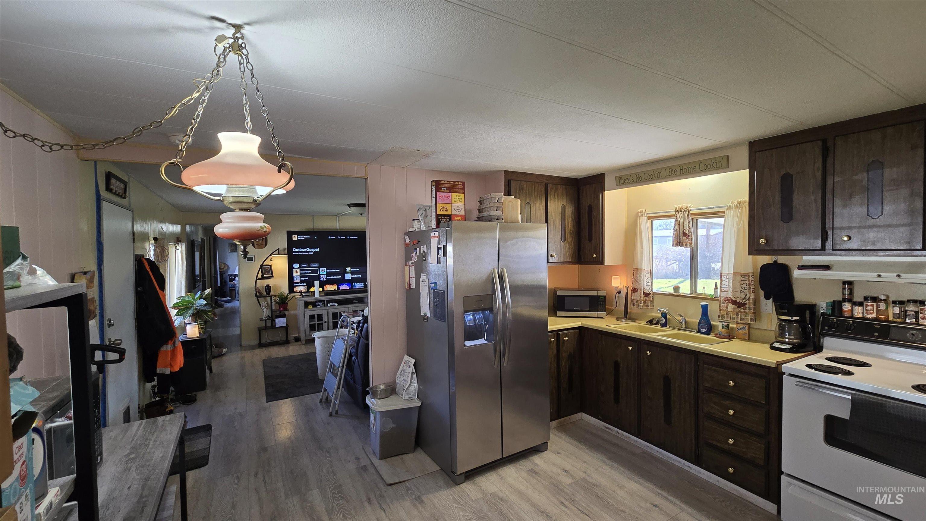 798 Dolson Lane Eagle, ID 83616 - Photo 21 of 33 Kitchen featuring dark wood finish cabinetry, stainless steel appliances, light wood-style flooring, and light countertops