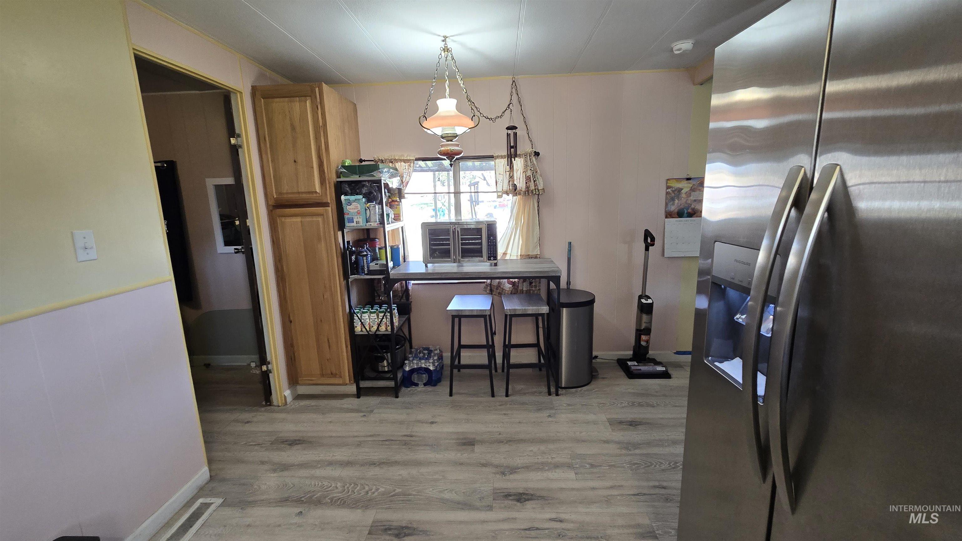 798 Dolson Lane Eagle, ID 83616 - Photo 22 of 33 Kitchen featuring stainless steel fridge, light wood finished floors, wood finish cabinets, and pendant lighting