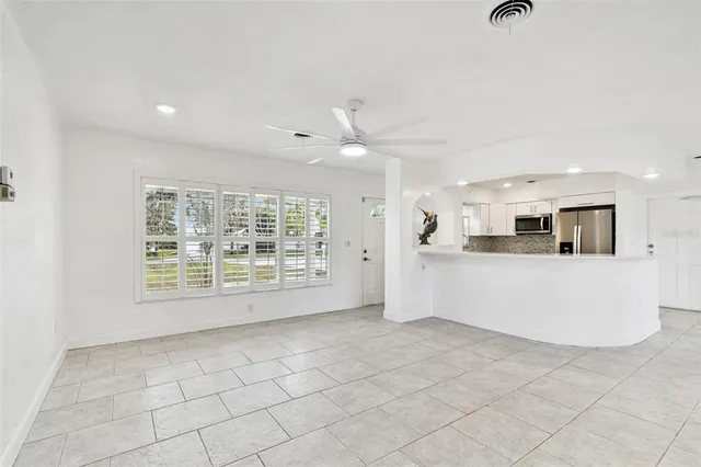 a view of open kitchen with granite countertop a white cabinets a sink and a large window