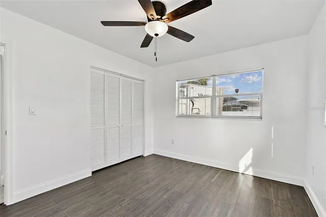 an empty room with wooden floor and ceiling fan