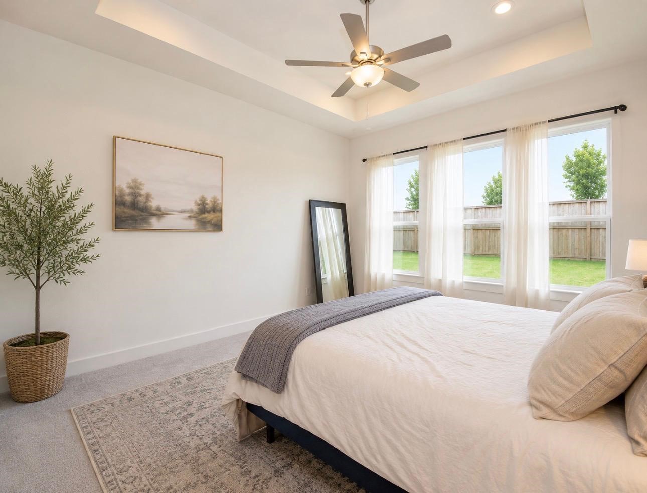 31915 Sky Rdg Lane Fulshear, TX 77441 - Photo 26 of 38 This inviting bedroom features a cozy bed with neutral bedding, a modern ceiling fan, and large windows that let in ample natural light. The room is tastefully decorated with a framed landscape painting and a potted plant, creating a serene atmosphere.