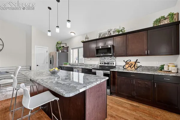 a kitchen with granite countertop stainless steel appliances a sink counter space and wooden floor