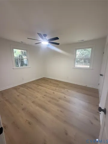 en empty room with windows and ceiling fan