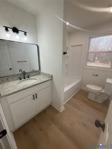 a bathroom with a granite countertop sink mirror vanity and toilet
