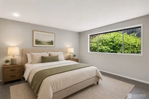 a bedroom with a bed painting on the wall and a large window