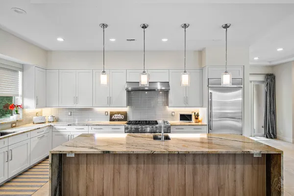 a kitchen with a stove a sink a refrigerator and chairs