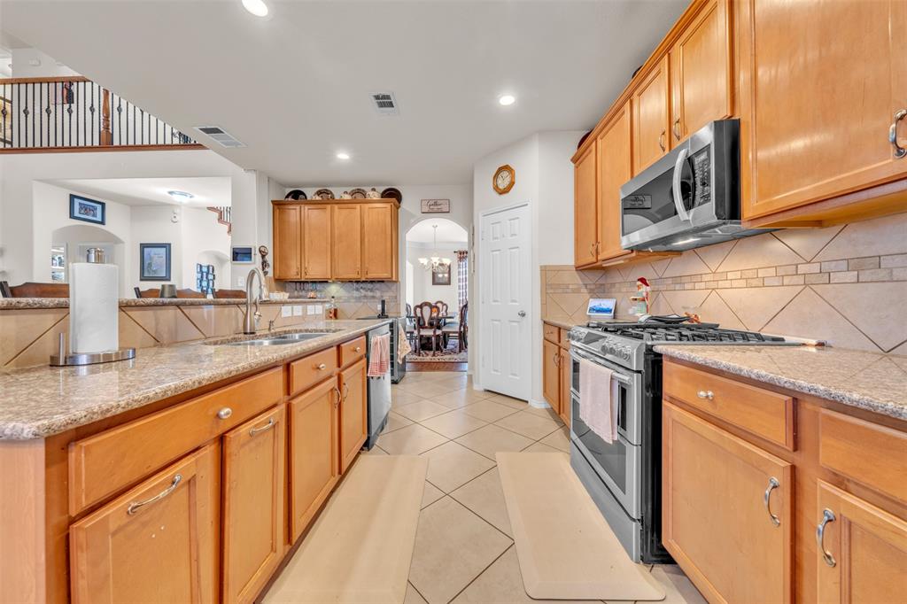 2244 Condor Street Grand Prairie, TX 75052 - Photo 13 of 37 a large kitchen with stainless steel appliances granite countertop a stove a sink and a microwave