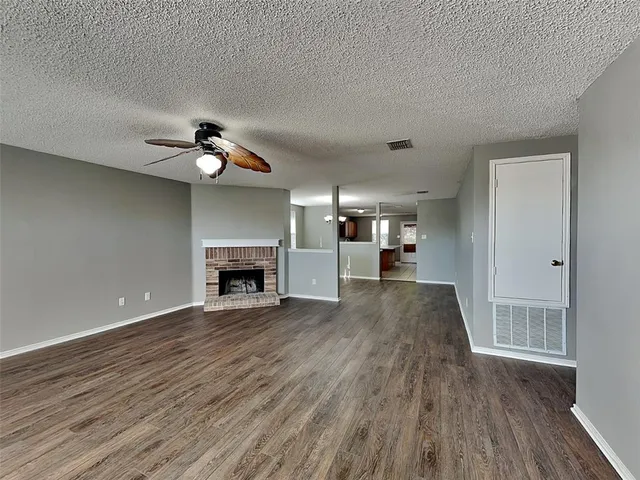 a view of empty room with a fireplace and wooden floor