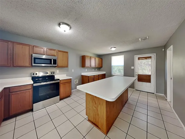 a large kitchen with stainless steel appliances a stove top oven a sink dishwasher and a refrigerator