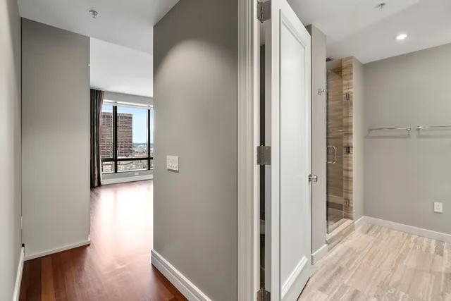 a view of a hallway with wooden floor and a bathroom