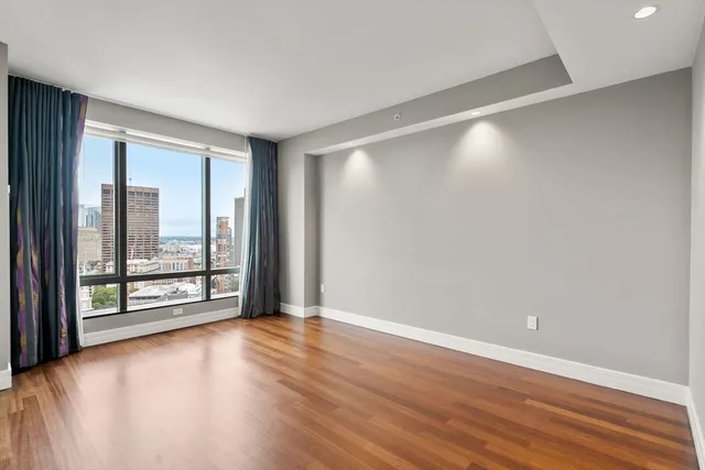 a view of an empty room with wooden floor and a window