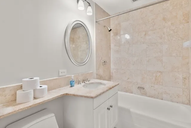 a bathroom with a sink vanity granite tub and a mirror