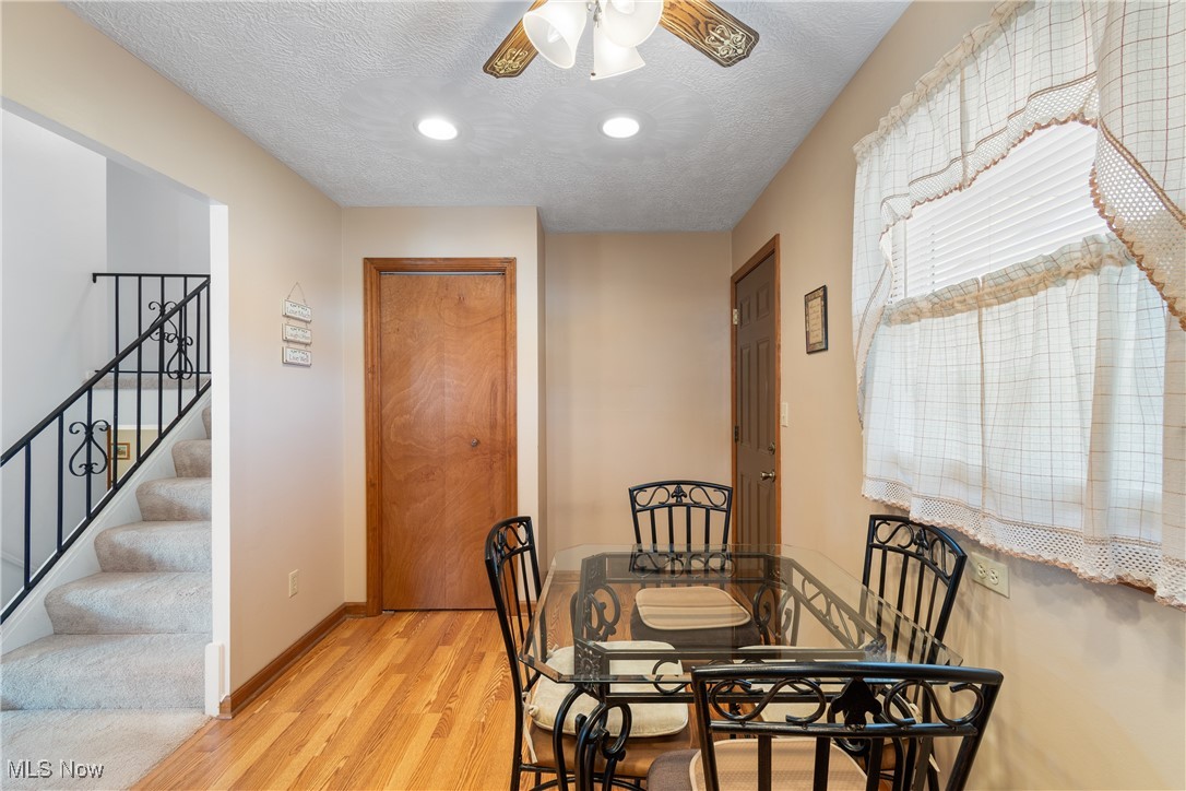 447 Center Road Bedford, OH 44146 - Photo 12 of 33 Dining area featuring light wood finished floors, baseboards, a ceiling fan, stairway, and a textured ceiling
