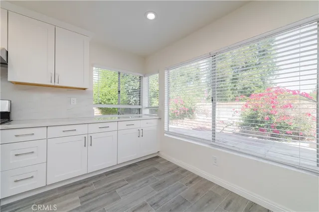 a kitchen with granite countertop white cabinets window and a sink