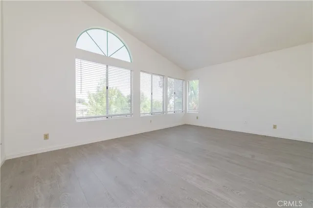 an empty room with wooden floor windows and outdoor view