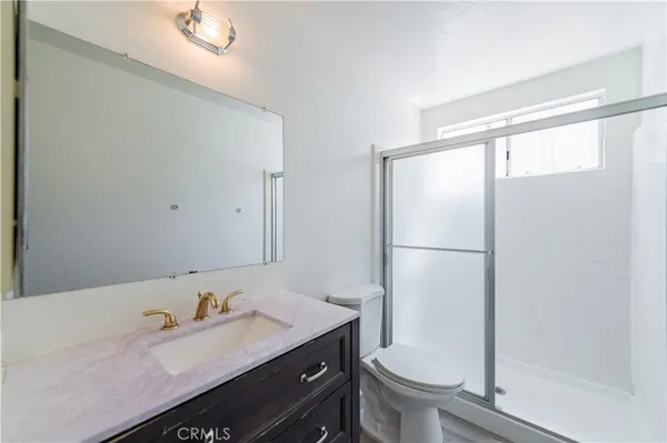 a bathroom with a granite countertop sink toilet and a mirror