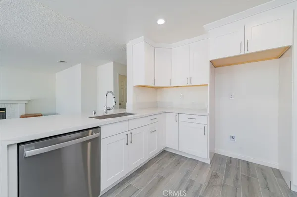 a kitchen with a sink dishwasher and cabinets with wooden floor