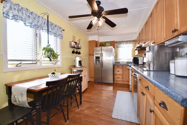 a kitchen with stainless steel appliances kitchen island granite countertop a table chairs in it and wooden floors