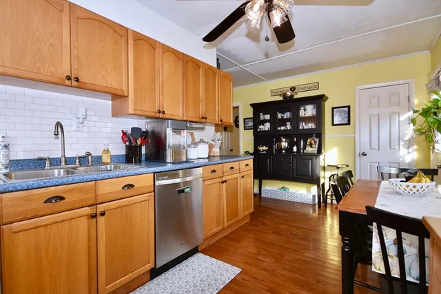 a kitchen with stainless steel appliances granite countertop a refrigerator a sink dishwasher stove and white cabinets with wooden floor