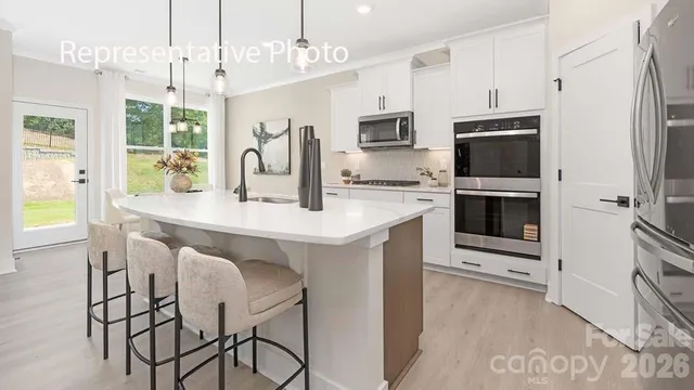 a kitchen with stainless steel appliances a white table chairs sink refrigerator and microwave