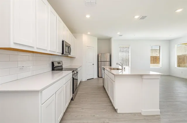 a view of kitchen with stainless steel appliances granite countertop white cabinets and refrigerator