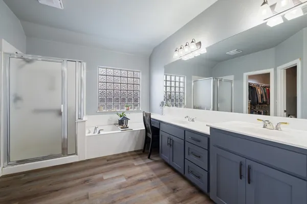 a bathroom with a granite countertop double vanity sink a bathtub and shower