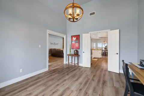 a hallway with wooden floor chandelier and entryway