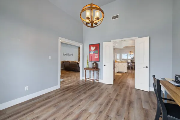 a hallway with wooden floor chandelier and entryway