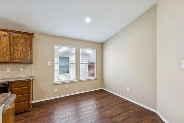 an empty room with wooden floor cabinet and windows