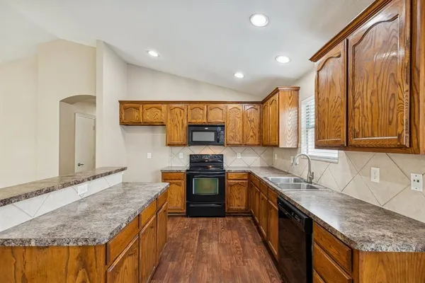 a kitchen with stainless steel appliances granite countertop wooden cabinets a stove top oven a sink and dishwasher