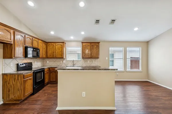 a kitchen with stainless steel appliances granite countertop wooden cabinets a stove top oven a sink and dishwasher