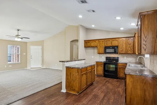 a kitchen with stainless steel appliances granite countertop wooden cabinets a stove top oven and sink