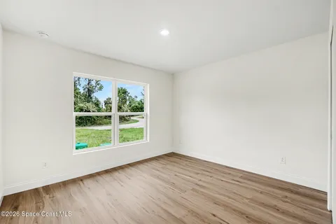 an empty room with wooden floor and window