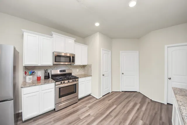 a kitchen with stainless steel appliances a white cabinets and a wooden floor