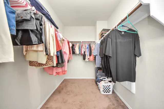a view of walk in closet with clothes and shoes