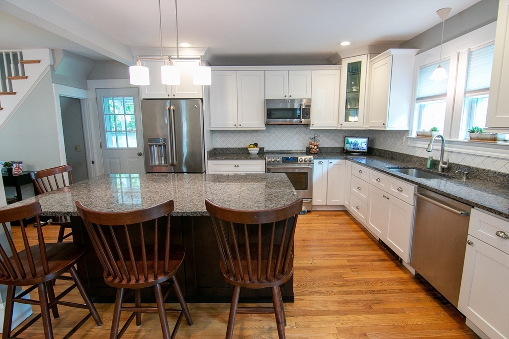 a kitchen with stainless steel appliances granite countertop a kitchen island hardwood floor sink stove dining table and chairs