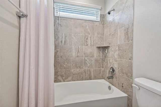 a bathroom with a granite countertop sink a toilet a mirror and bathtub