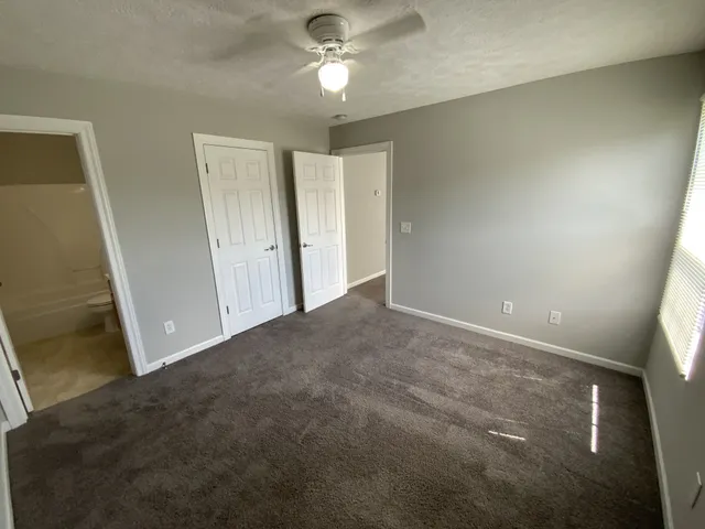 an empty room with closet and a ceiling fan
