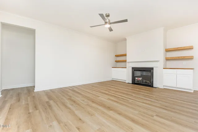 an empty room with wooden floor fireplace and windows