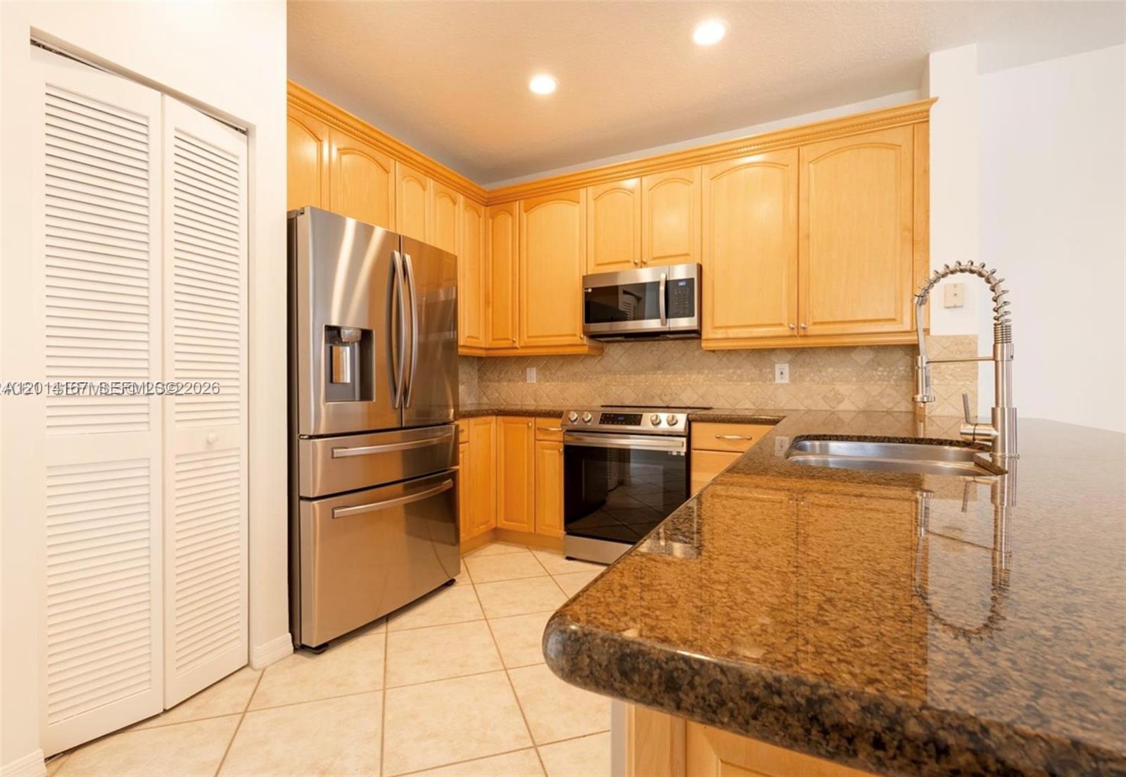 618 Willow Bend Road, Unit 618 Weston, FL 33327 - Photo 6 of 9 a kitchen with stainless steel appliances granite countertop a refrigerator a stove and a sink with wooden floor