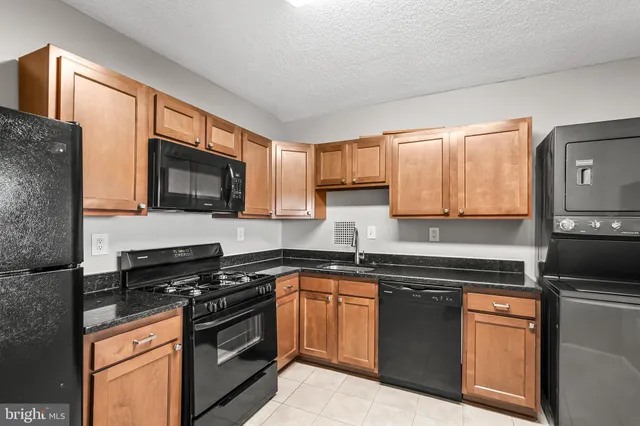 a kitchen with stainless steel appliances granite countertop a stove top oven a sink dishwasher and a microwave oven with cabinets