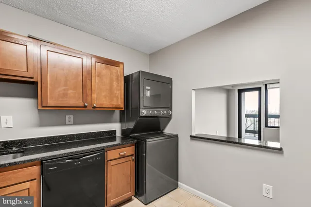 a kitchen with granite countertop a sink cabinets and stainless steel appliances