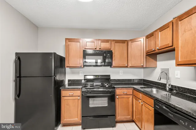 a kitchen with stainless steel appliances granite countertop a refrigerator a stove and a sink