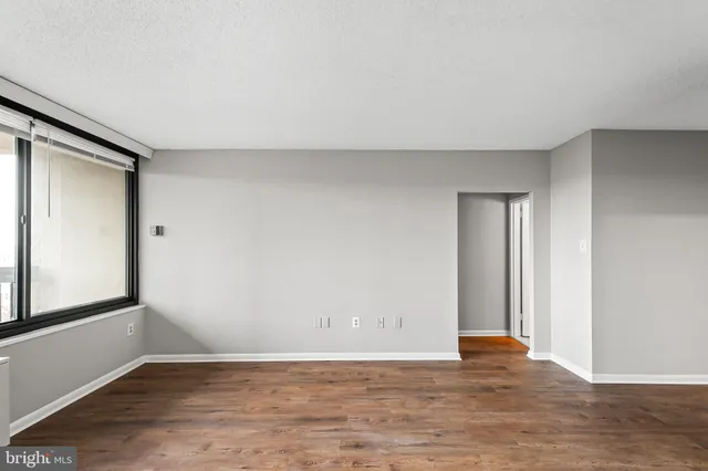 an empty room with wooden floor and windows