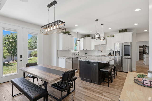 10676 Urban Rdg Cove South Jordan, UT 84095 - Photo 7 of 48 Kitchen featuring an oversized island with countertop seating, white shaker cabinetry, stainless steel appliances, and wood-finish flooring