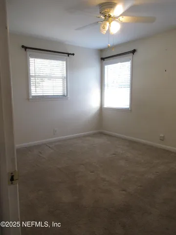 en empty room with windows and chandelier fan