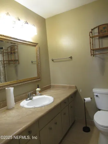 a bathroom with a granite countertop sink toilet and mirror