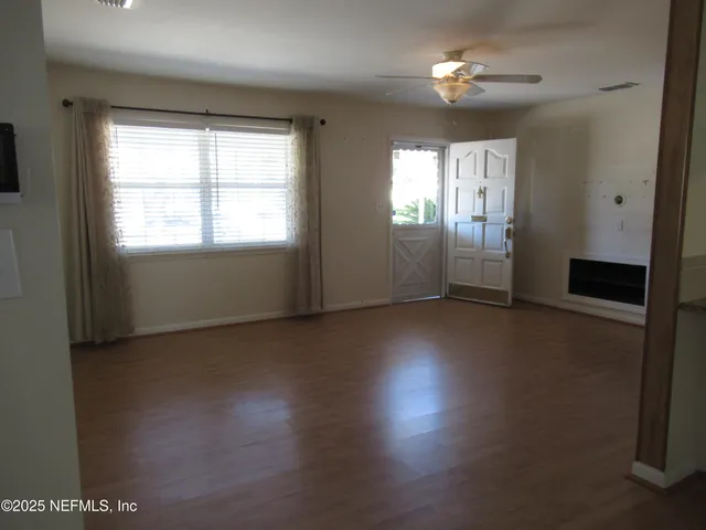 an empty room with windows and chandelier fan